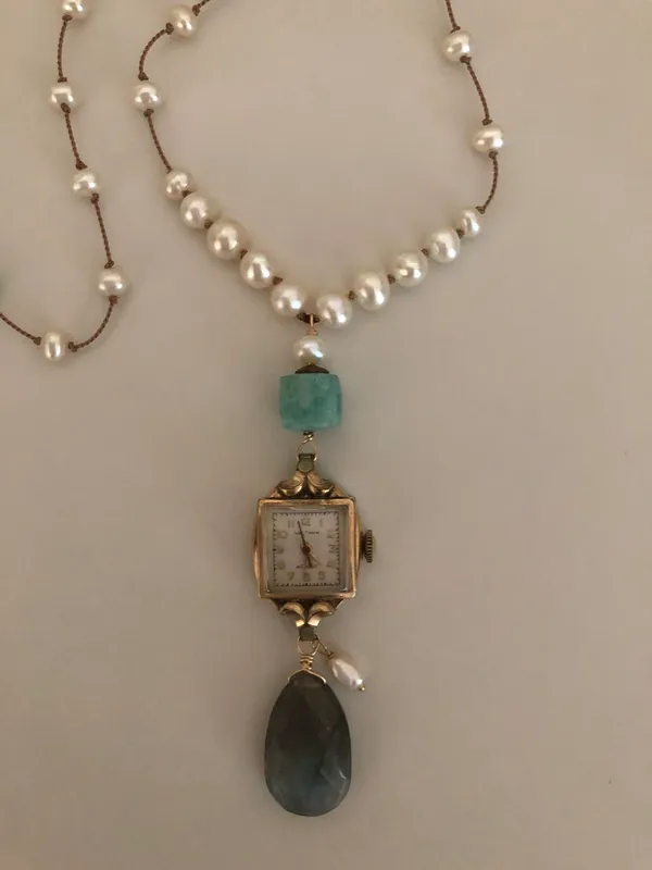 a necklace with a watch and pearls on it